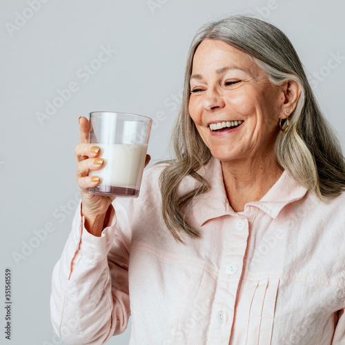 Valokuva Cheerful senior woman drinking a glass of milk