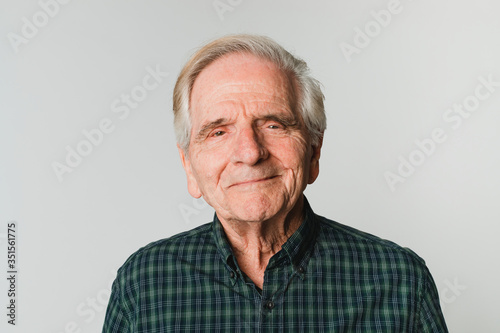 Elderly Caucasian man with white hair smiling on gray background photo
