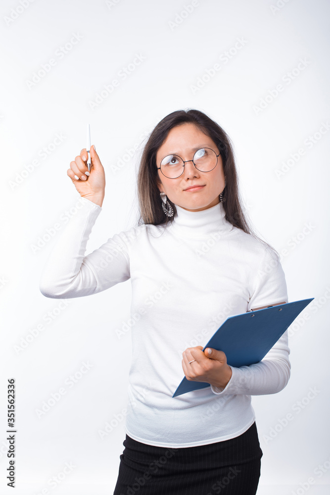 Thoughtful girl wearing glasses is holding a paper clipboard and a pen over white. Thoughtful girl wearing glasses is holding a paper clipboard and a pen over white.