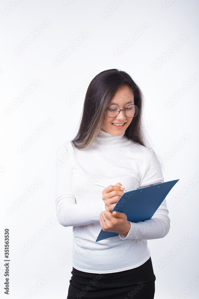 Cheerful girl wearing glasses is writing something on a clipboard over white. Cheerful girl wearing glasses is writing something on a clipboard over white.