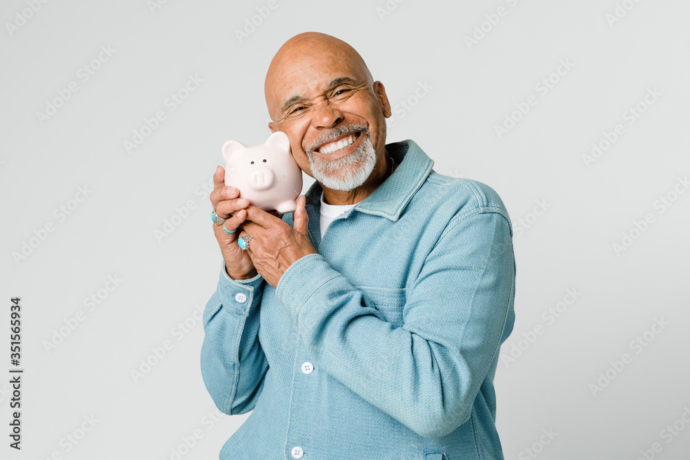 Happy retired man holding his piggy bank