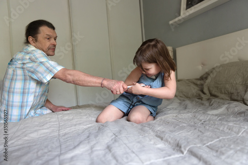 father takes away a smart phone from child girl, children’s digital addiction, the concept of children and gadgets