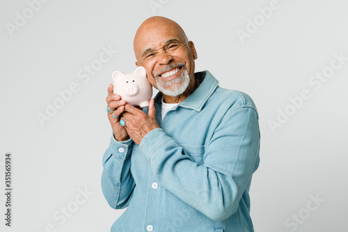 Fotografija Happy retired man holding his piggy bank