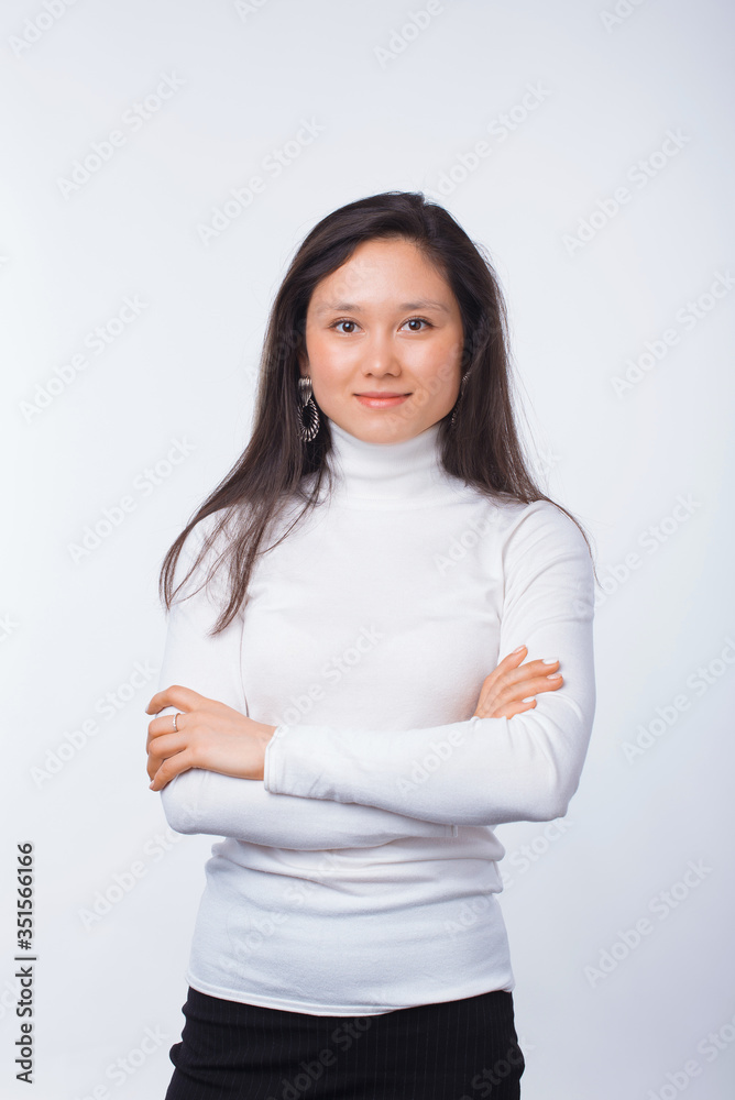 Portrait of a young smiling woman looking at the camera with arms crossed over white.