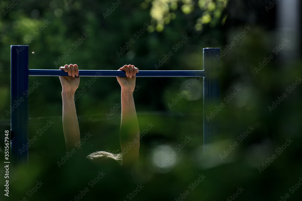 girl pulls herself up on the horizontal bar. Concept - outdoor sports girl pulls herself up on the horizontal bar. Concept - outdoor sports