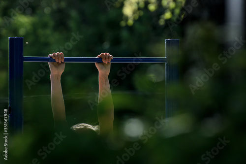 girl pulls herself up on the horizontal bar. Concept - outdoor sports