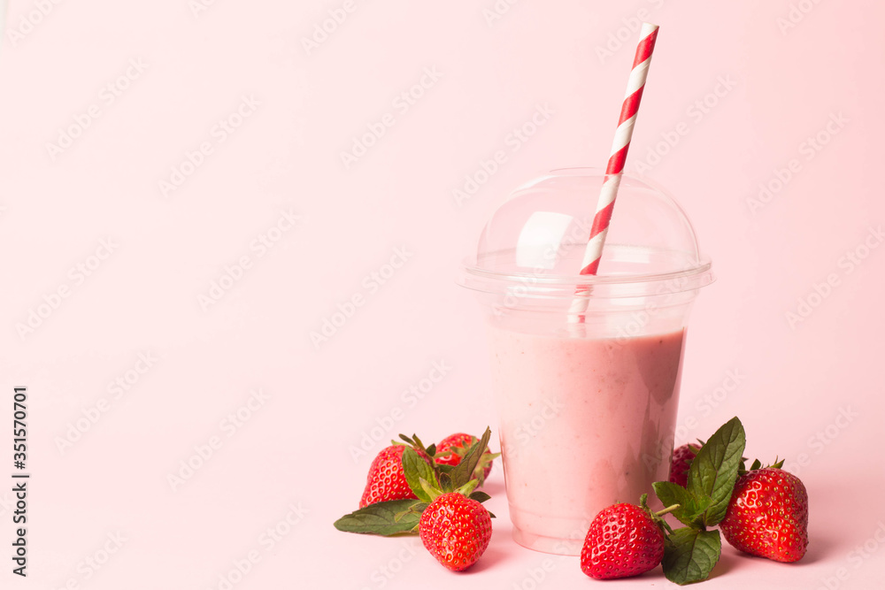 Glass of fresh strawberry milkshake, smoothie and fresh strawberries on pink, white and wooden background. Healthy food and drink concept. Glass of fresh strawberry milkshake, smoothie and fresh strawberries on pink, white and wooden background. Healthy food and drink concept.