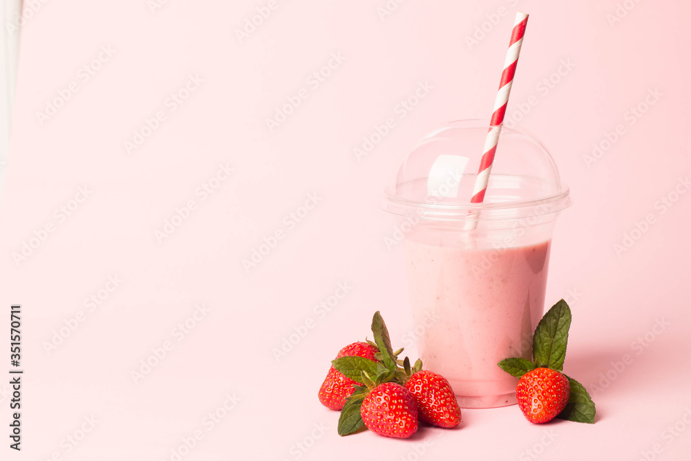 Glass of fresh strawberry milkshake, smoothie and fresh strawberries on pink, white and wooden background. Healthy food and drink concept. Glass of fresh strawberry milkshake, smoothie and fresh strawberries on pink, white and wooden background. Healthy food and drink concept.