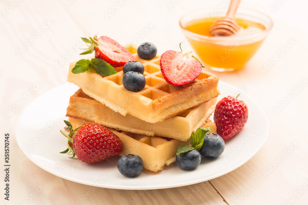 Fresh homemade food of berry Belgian waffles with honey, chocolate, strawberry, blueberry, maple syrup and cream. Healthy dessert breakfast concept with juice Fresh homemade food of berry Belgian waffles with honey, chocolate, strawberry, blueberry, maple syrup and cream. Healthy dessert breakfast concept with juice