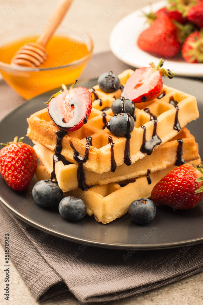 Fresh homemade food of berry Belgian waffles with honey, chocolate, strawberry, blueberry, maple syrup and cream. Healthy dessert breakfast concept with juice Fresh homemade food of berry Belgian waffles with honey, chocolate, strawberry, blueberry, maple syrup and cream. Healthy dessert breakfast concept with juice