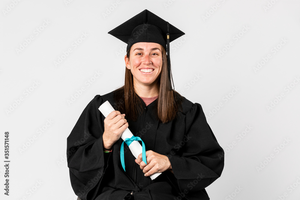 Proud girl in a graduation gown holding her diploma Proud girl in a graduation gown holding her diploma