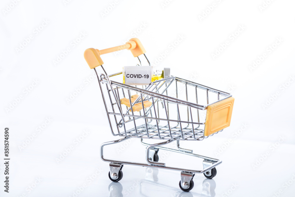 Yellow shopping cart with Covid-19 vaccine on a white background, isolated, close up.
Be careful with coronavirus while shopping!