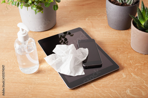 disinfecting tablet computer and smartphone screen, eliminating germs coronavirus bacteria photo