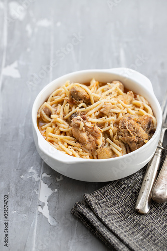 spaghetti with chicken in white bowl on ceramic background