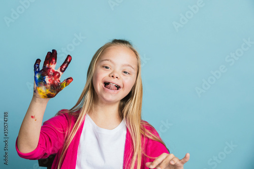 Cute girl with Down Syndrome playing with paints photo