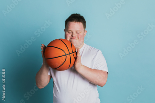 Cute athletic boy with down syndrome holding a basketball photo
