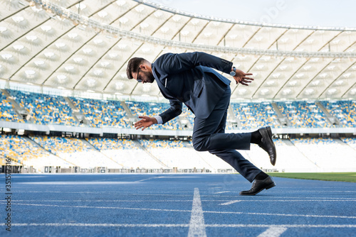 side view of young businessman in suit running at stadium