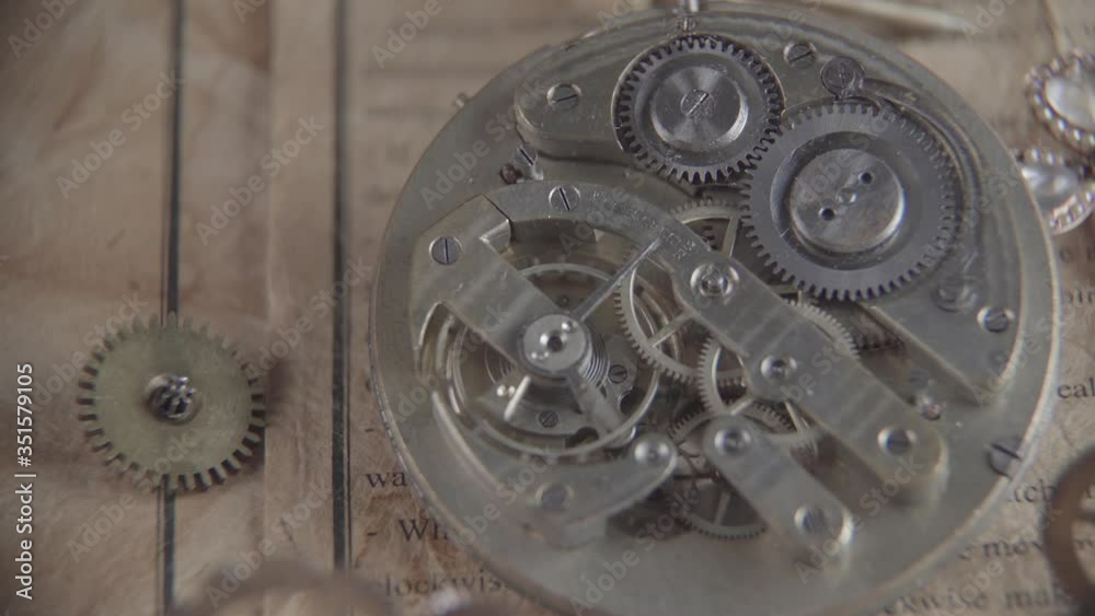 Macro shot of an antique vintage tick-tock mechanism in motion; on the background of cogwheels and old paper