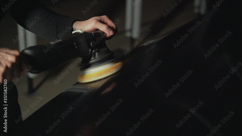 Car detailing - Hands with orbital polisher in auto repair shop. Polished black car. Car detailing - Hands with orbital polisher in auto repair shop. Polished black car.