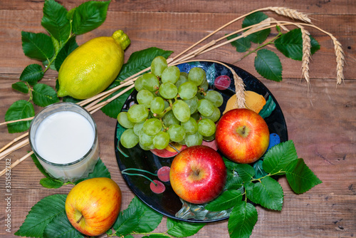 lemon  apples  green grapes  wheat and a glass with milk on a wooden table.