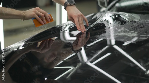 Foto professional applying protective film to the red car