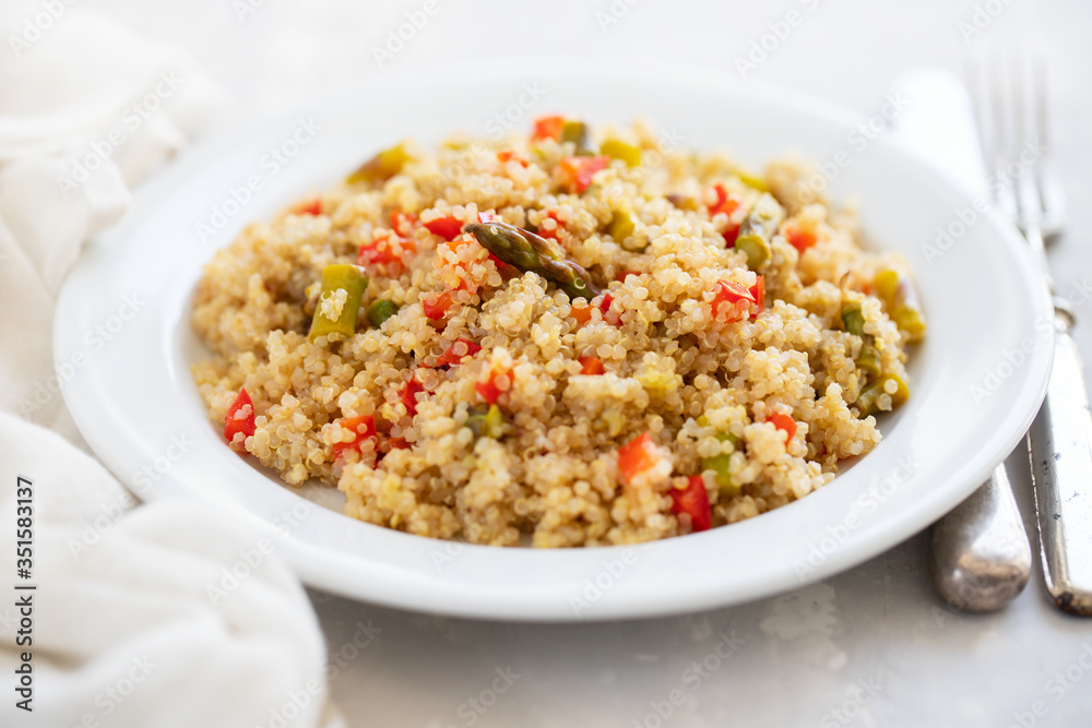 quinoa with vegetables on white plate on ceramic background