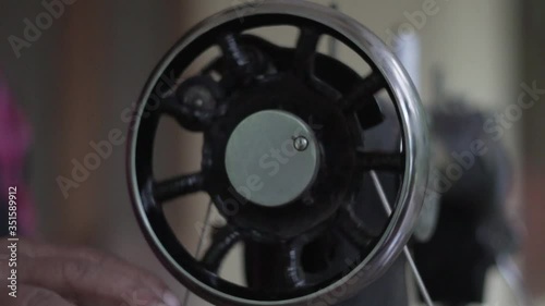 Close up of old sewing machine with women's hands on wheel slow motion