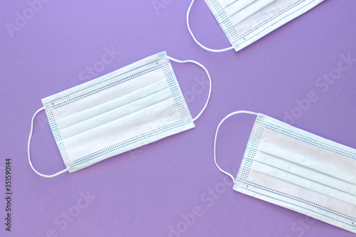 three white medical mask to protect the face from the virus on a blue purple background with space for text