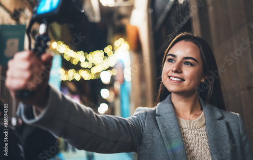 Tourist female blogger shooting photo for social media with digital camera. Smiling  woman filming videovlog on light night europe city photo