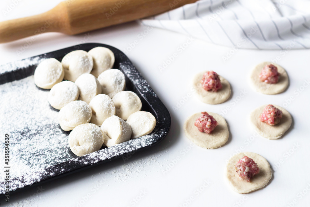 raw dumplings lie on a tray, near tortillas, sculpt dumplings, Russian national cuisine raw dumplings lie on a tray, near tortillas, sculpt dumplings, Russian national cuisine