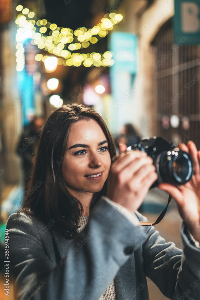 Photographer young girl with retro camera take photo on background bokeh light in evening street city,  photo hobby