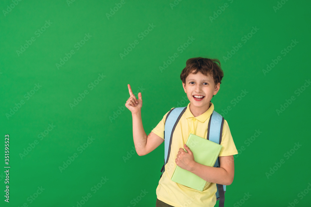 cute smart boy with a school bag and a book in his hand directs attention cute smart boy with a school bag and a book in his hand directs attention