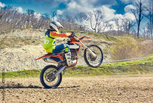 Motocross, a rider stands on the rear wheel of a bike, Riding on the rear wheel. Extreme, industrial, motorcycle cross-country riding for extreme.