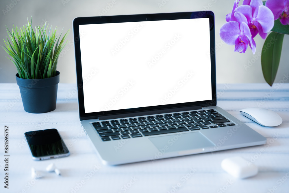 Fototapeta premium Laptop computer white blank screen on work table front view. Copy space, home and office workspace concept, laptop mockup.