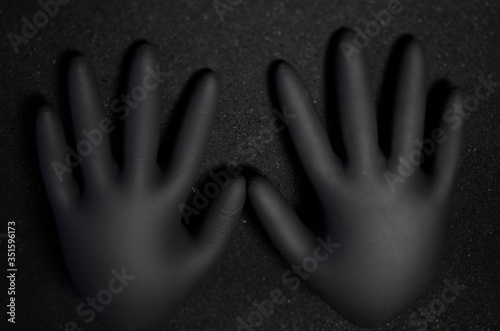 Beautiful black disposable medical gloves on a black background. Concept: gloved Hands appear out of the dark. There is space for text.