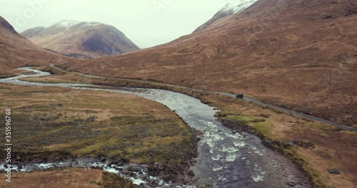 Wide perspective shows car driving through mounatinous landscape photo