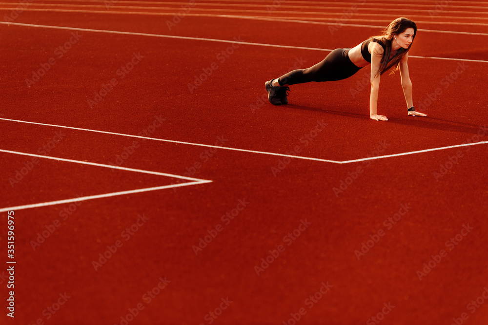  Wonderful fitness woman doing sport exercises in the stadium.