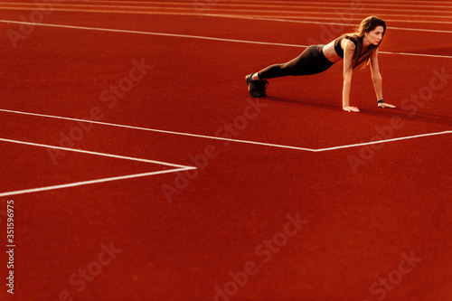  Wonderful fitness woman doing sport exercises in the stadium.