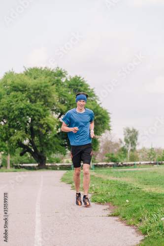 A young athlete in a blue T-shirt runs around the stadium © Denis