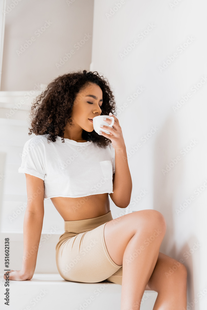 young african american woman sitting on stairs and drinking coffee young african american woman sitting on stairs and drinking coffee