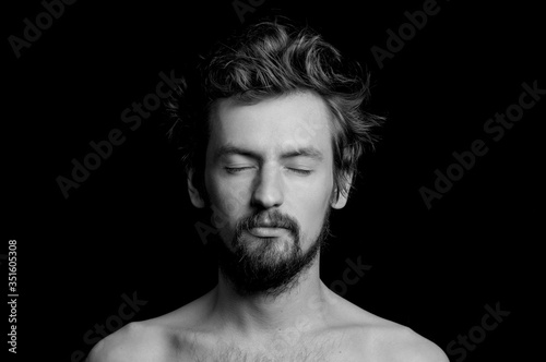 portrait of a guy with a beard and tousled hair on a black background