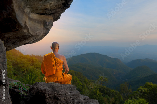 Buddhist monk in meditation Under the big stones in nature on high mountain.