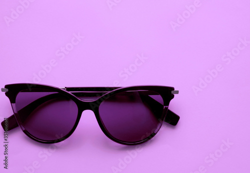 cat-shaped sunglasses in the bottom corner on a purple, violet background. Place for text, inscriptions. Rest, summer, fashion accessories, women's little things, pleasant shopping