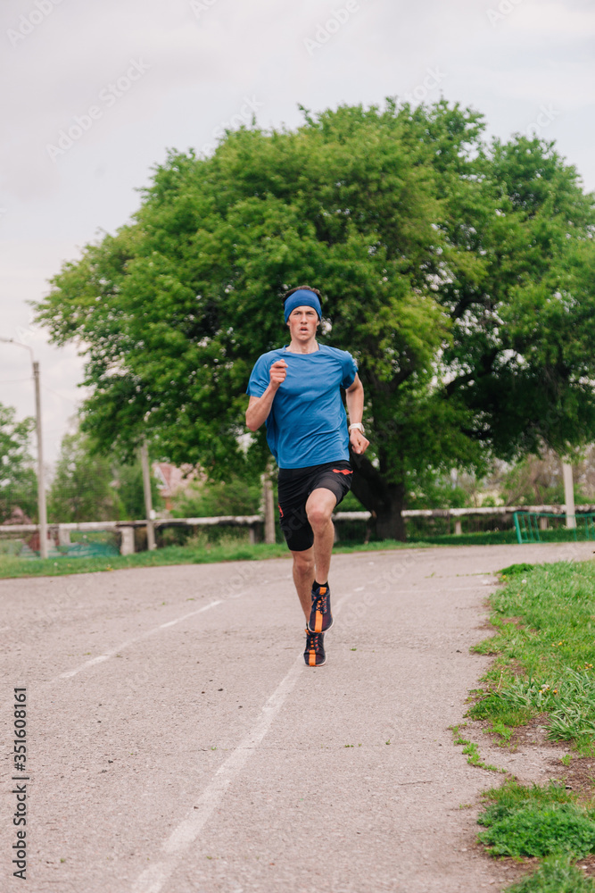 A young athlete in a blue T-shirt runs around the stadium A young athlete in a blue T-shirt runs around the stadium