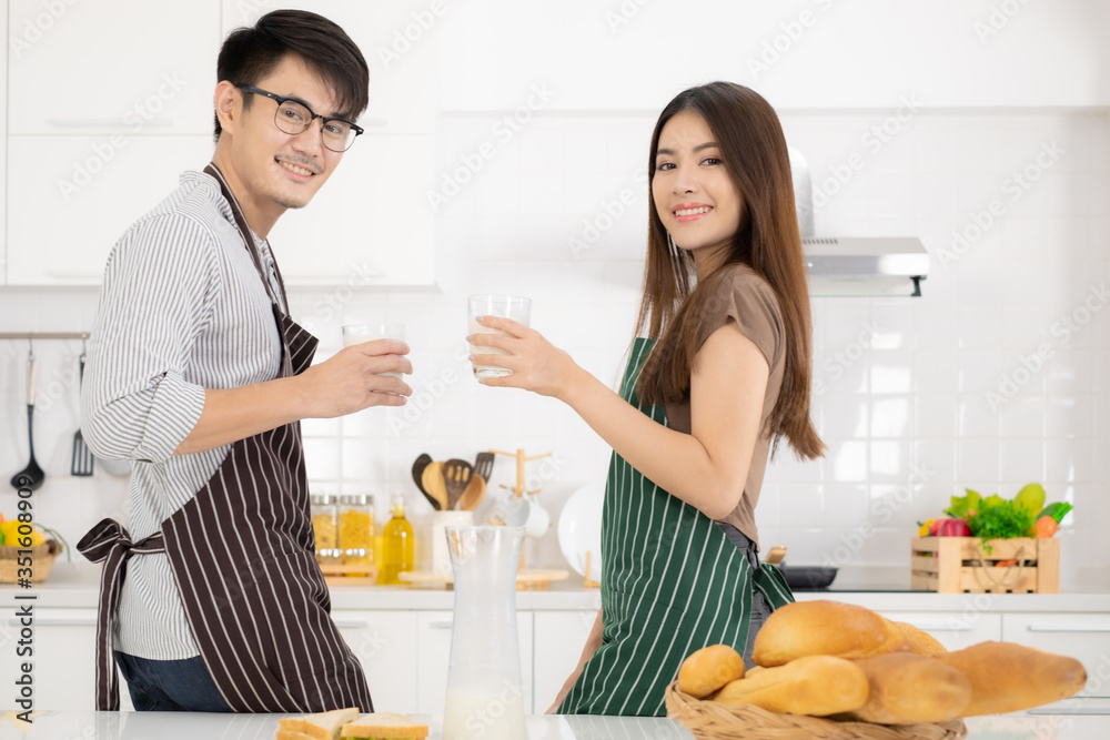 Young Asian couple enjoying breakfast with milk bread and sanwich in white kitchen. Young Asian couple enjoying breakfast with milk bread and sanwich in white kitchen.