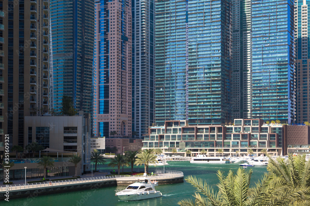 Fototapeta premium Bright cityscape, postcard view of the modern city. The boat floats along the canal along tall office buildings and residential skyscrapers.