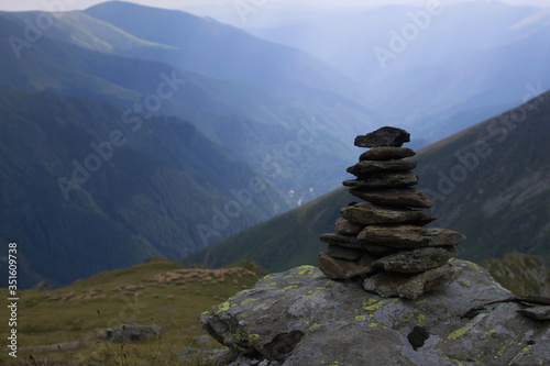 Balancing rock art. Stones balance on top of each other on a stone on top of a mountain. З Zen stones or a stack of zen against a background of blue mountains.