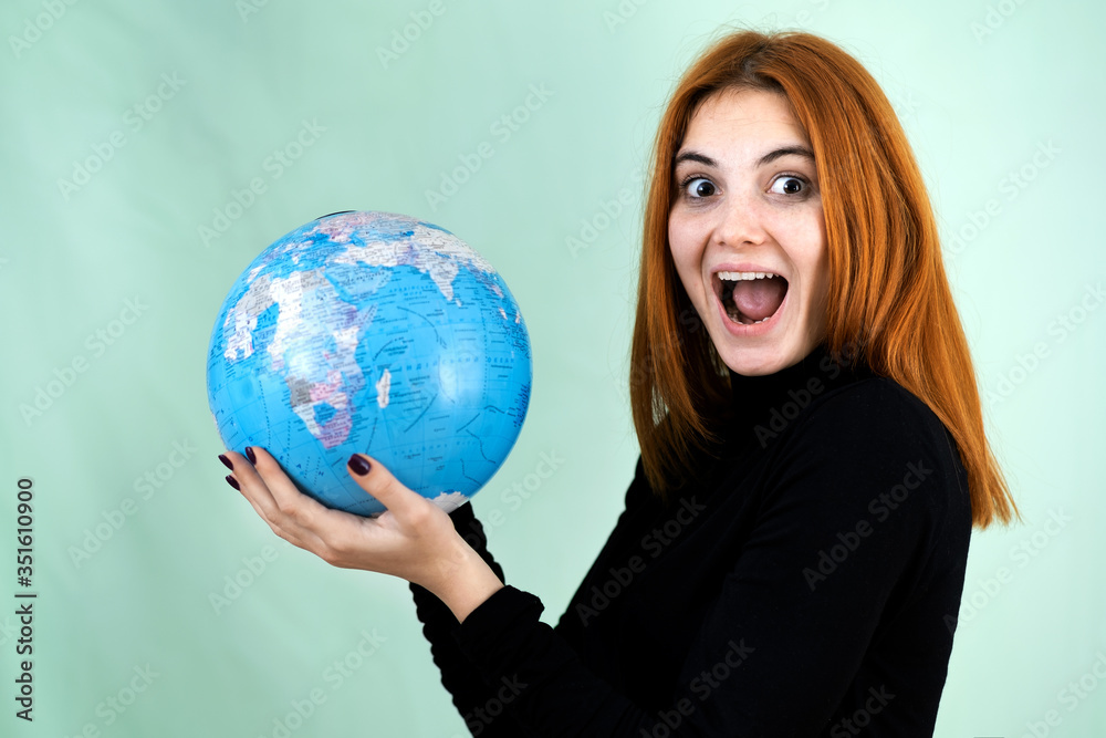 Portrait of a happy young woman holding geographic globe of the world in her hands. Travel destination and planet protection concept. Portrait of a happy young woman holding geographic globe of the world in her hands. Travel destination and planet protection concept.