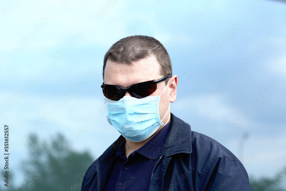 Close portrait Young man in a protective mask and black goggles. Close-up. Copy space. The city is big. Pandemic protective measures. Coronavirus concept COVID-19 Close portrait Young man in a protective mask and black goggles. Close-up. Copy space. The city is big. Pandemic protective measures. Coronavirus concept COVID-19