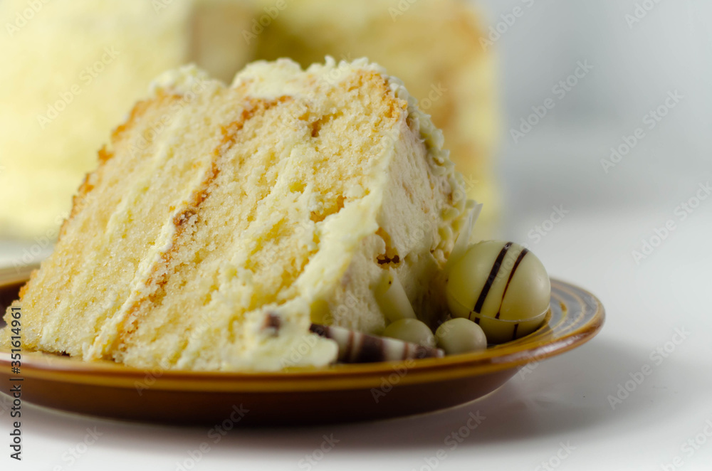 A piece of layered white cream cake with confectionery decorations